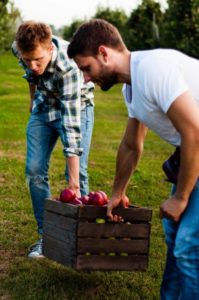 śwoeże_jablka_w_koszu_niesione_przez _dwoch_mlodych_ludzi